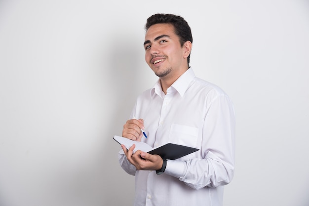 Jovem empresário com notebook posando em fundo branco.