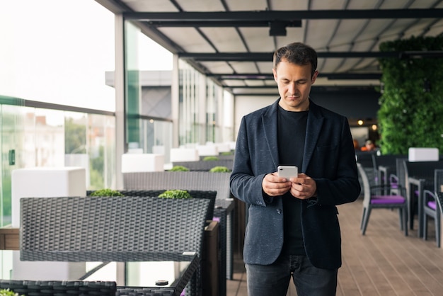 Jovem empresário digitando em seu telefone inteligente em um café