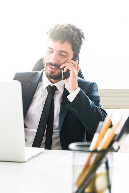 Foto grátis jovem empresário falando no celular no local de trabalho