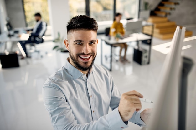 Foto grátis jovem empresário feliz escrevendo no quadro enquanto trabalhava no escritório