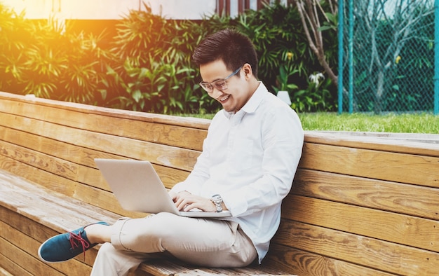 Jovem empresário feliz trabalhando no laptop no jardim