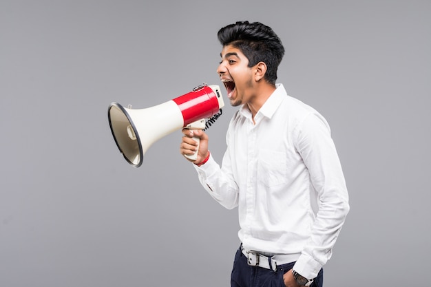 Jovem empresário indiano anunciando em um megafone na parede cinza