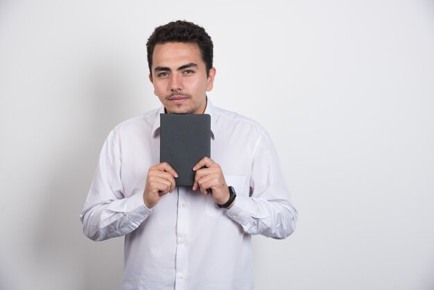 Jovem empresário posando com notebook em fundo branco.