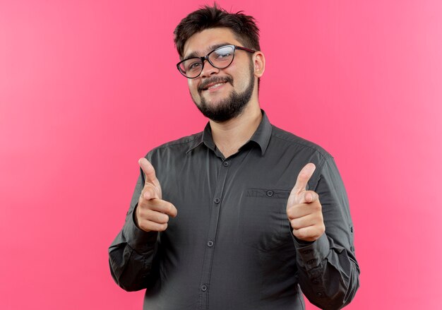 Jovem empresário satisfeito usando óculos, mostrando gestos isolados na parede rosa