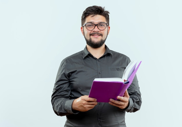 Jovem empresário satisfeito usando óculos, segurando um livro isolado no fundo branco