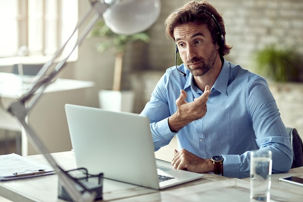 Foto grátis jovem empresário se comunicando com alguém enquanto faz videoconferência no escritório