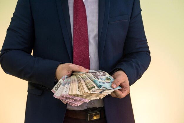 Jovem empresário segurando uma enorme quantidade de dinheiro. novas notas de uah da ucrânia 1000 e 500 nas mãos de um empresário. lucro. Foto Premium