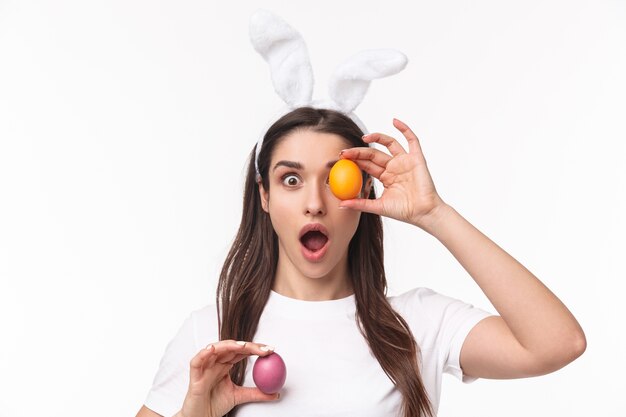 Jovem encantadora com orelhas de coelho segurando um ovo colorido