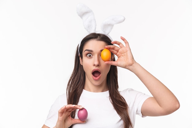 Jovem encantadora com orelhas de coelho segurando um ovo colorido