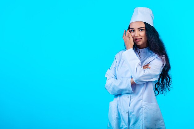 Jovem enfermeira com uniforme isolado fecha os braços e sorri