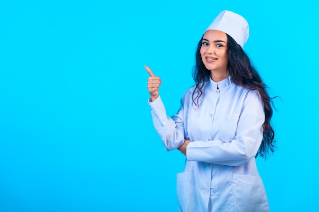 Jovem enfermeira com uniforme isolado parece alegre e faz sinal positivo