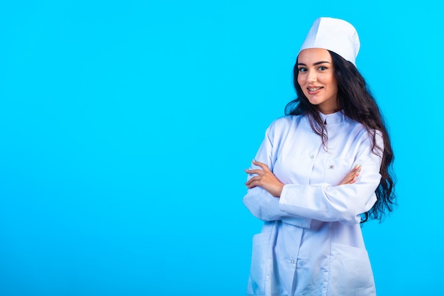 Jovem enfermeira em uniforme isolado fecha os braços e sorri.