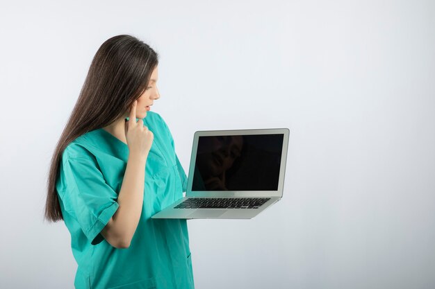 Jovem enfermeira olhando para laptop em branco.