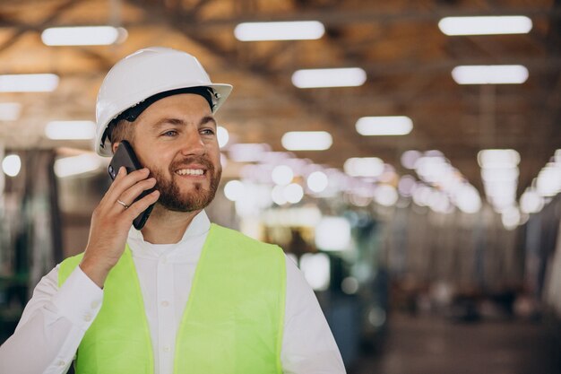 Jovem engenheiro trabalhando na fábrica, fazendo pedidos pelo telefone