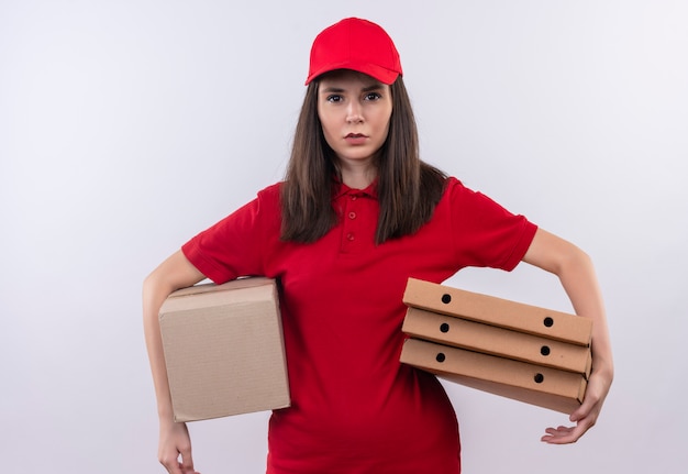 Jovem entregadora de camiseta vermelha com boné vermelho segurando uma caixa e uma caixa de pizza no fundo branco isolado