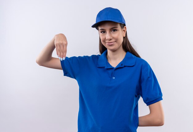 Jovem entregadora de uniforme azul e boné parecendo confiante gesticulando com as mãos, conceito de linguagem corporal