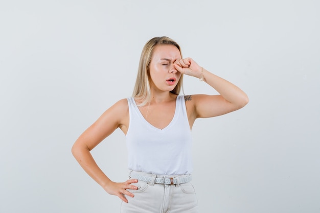 Jovem esfregando os olhos na blusa branca e parecendo preocupada