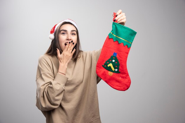 Jovem espantada parecendo surpresa e segurando a meia de natal.