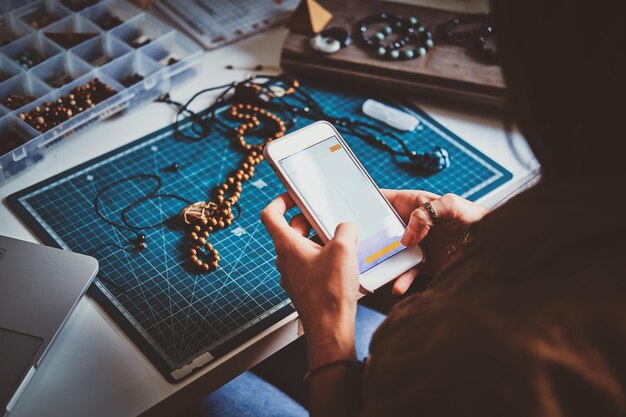 Jovem está fazendo foto de suas lindas pulseiras de miçangas via smartphone.