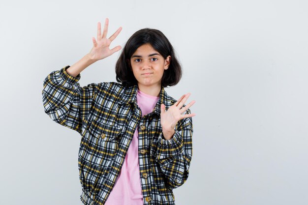 Jovem, esticando as mãos a ponto de parar em camisa xadrez e camiseta rosa e está linda.