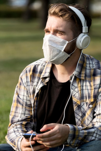 Jovem estiloso com máscara facial ouvindo música