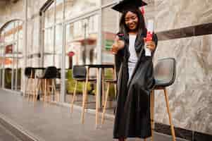 Foto grátis jovem estudante afro-americana com diploma posa ao ar livrexa