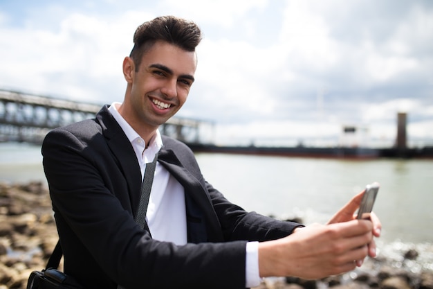 Jovem estudante animado fotografando na costa