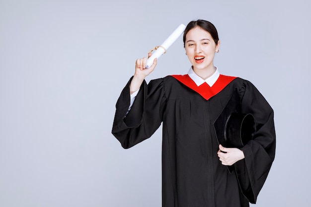 Jovem estudante com vestido e diploma posando com a boca aberta. Foto de alta qualidade