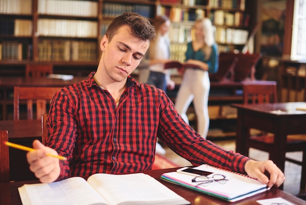 Jovem estudante estudando na biblioteca