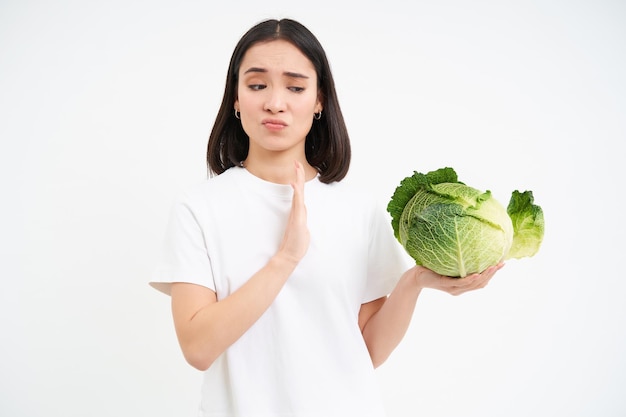 Foto grátis jovem expressa antipatia, rejeita comer repolho, não mostra gesto de recusa de parada isolado em branco