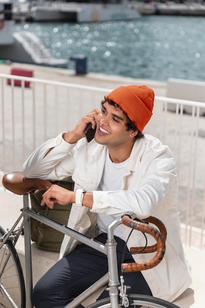 Jovem falando ao telefone ao lado de sua bicicleta