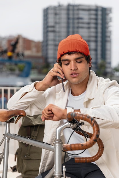 Foto grátis jovem falando ao telefone ao lado de sua bicicleta