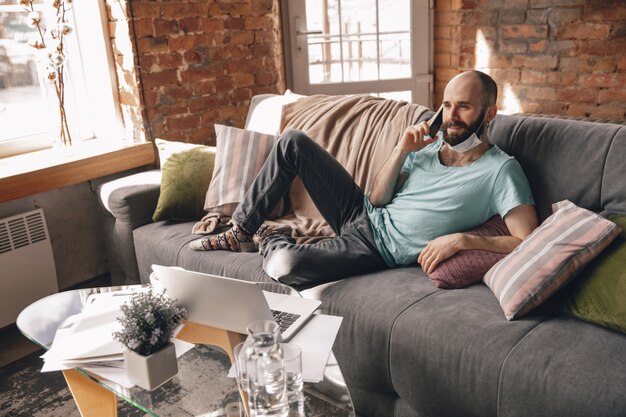 Jovem falando ao telefone em casa enquanto trabalhava em quarentena e como freelance