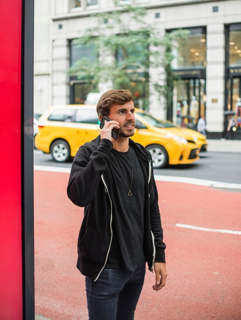 Jovem, falando ao telefone na rua