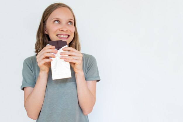 Jovem fascinada segurando a barra de chocolate em folha de ouro