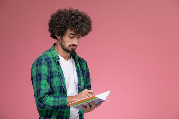 Foto grátis jovem fazendo anotações no fundo rosa