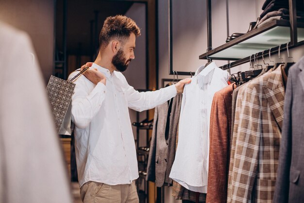 Jovem fazendo compras na loja de moda masculina e falando ao telefone