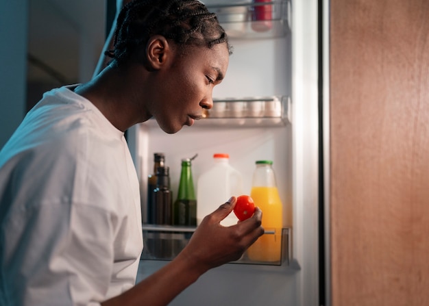 Foto grátis jovem fazendo um lanche no meio da noite em casa ao lado da geladeira