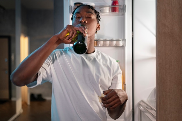 Jovem fazendo um lanche no meio da noite em casa ao lado da geladeira