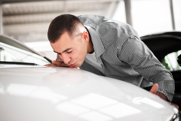 Foto grátis jovem feliz beijando seu carro novo