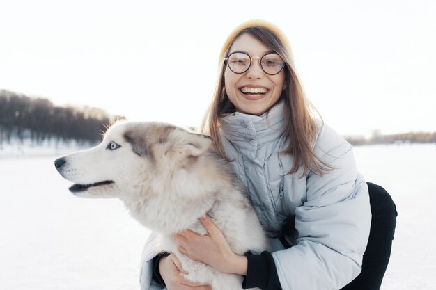 Jovem feliz brincando com cachorro husky siberiano em winter park