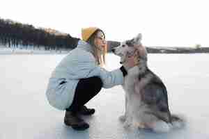 Foto grátis jovem feliz brincando com cachorro husky siberiano em winter park