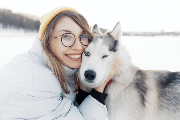 Jovem feliz brincando com cachorro husky siberiano em winter park