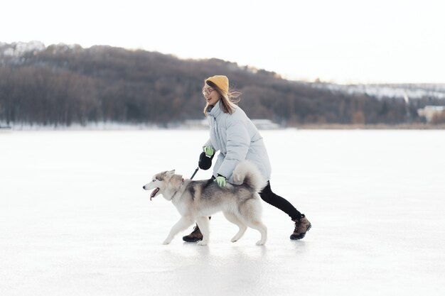 Jovem feliz brincando com cachorro husky siberiano em winter park