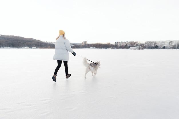 Foto grátis jovem feliz brincando com cachorro husky siberiano em winter park