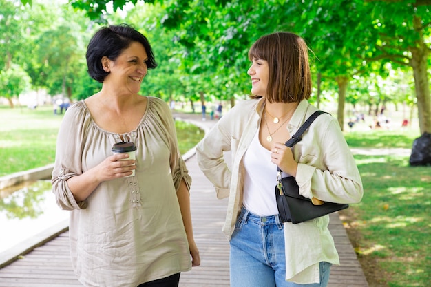 Jovem feliz e a mãe dela conversando e andando no parque