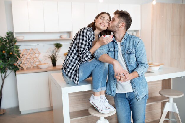 Jovem feliz e mulher na cozinha, café da manhã, casal juntos pela manhã, sorrindo, tomando chá