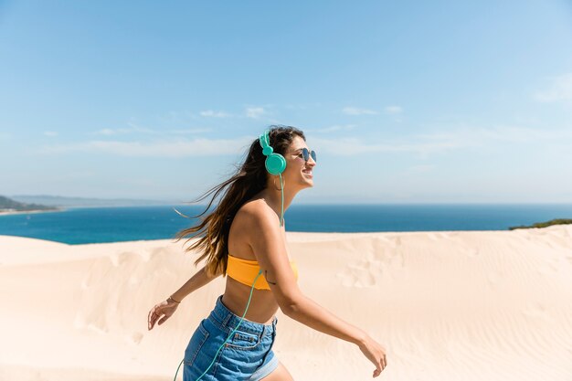 Jovem feliz em fones de ouvido na beira-mar