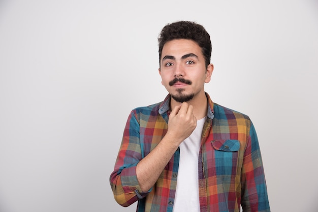 Jovem feliz posando sobre uma parede branca