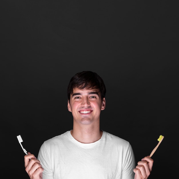 Jovem feliz segurando escovas de dentes